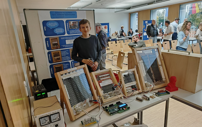 Ein Jugendlicher steht hinter einem Tisch auf dem ein Relais zu sehen ist