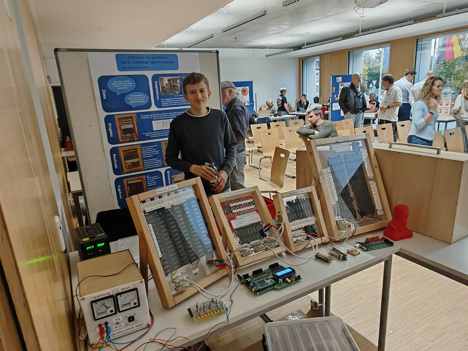Ein Jugendlicher steht hinter einem Tisch auf dem ein Relais zu sehen ist