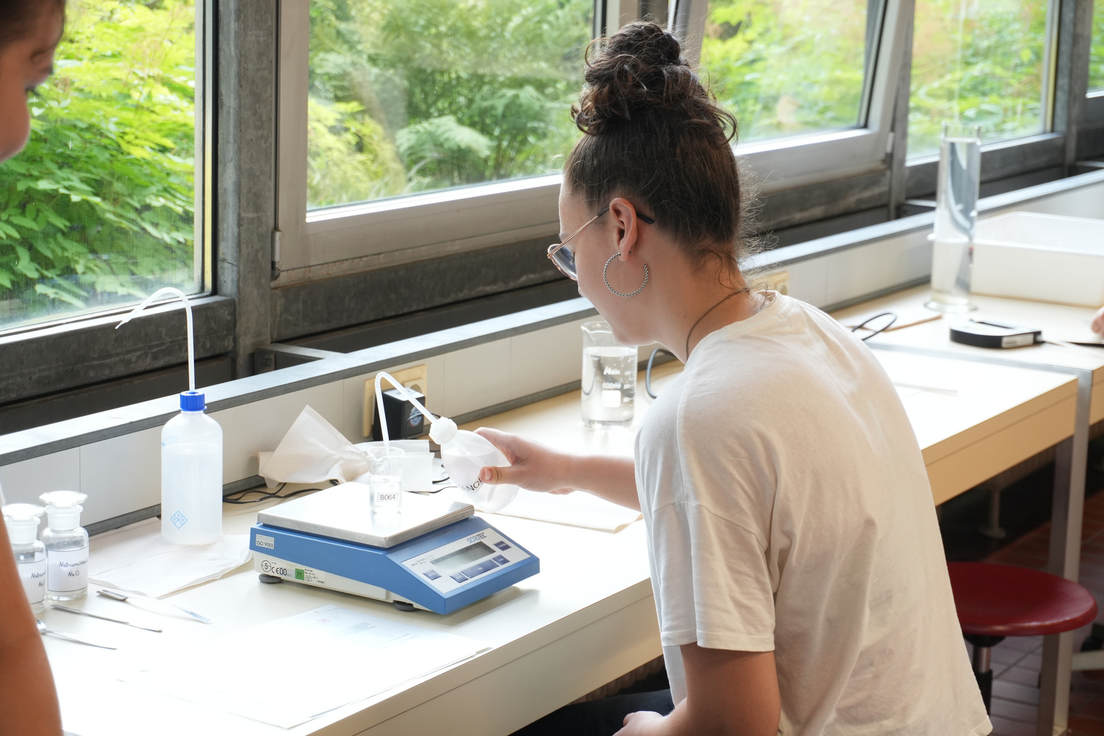 Ein Mädchen untersucht eine Wasserprobe mit Mikroplastik